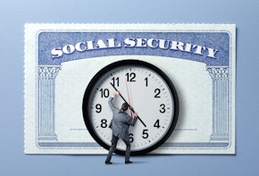 A man trying to stop the hands of a large clock that is attached to an even larger social security card.