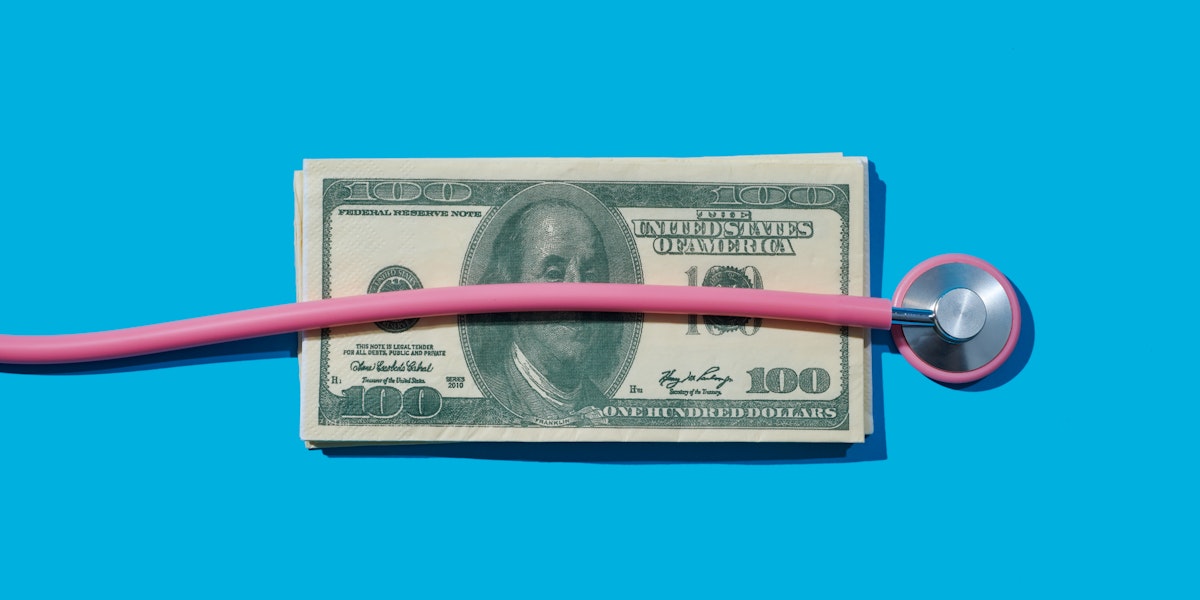 A pink stethoscope is on top of a pile of dollar bills against a blue background.