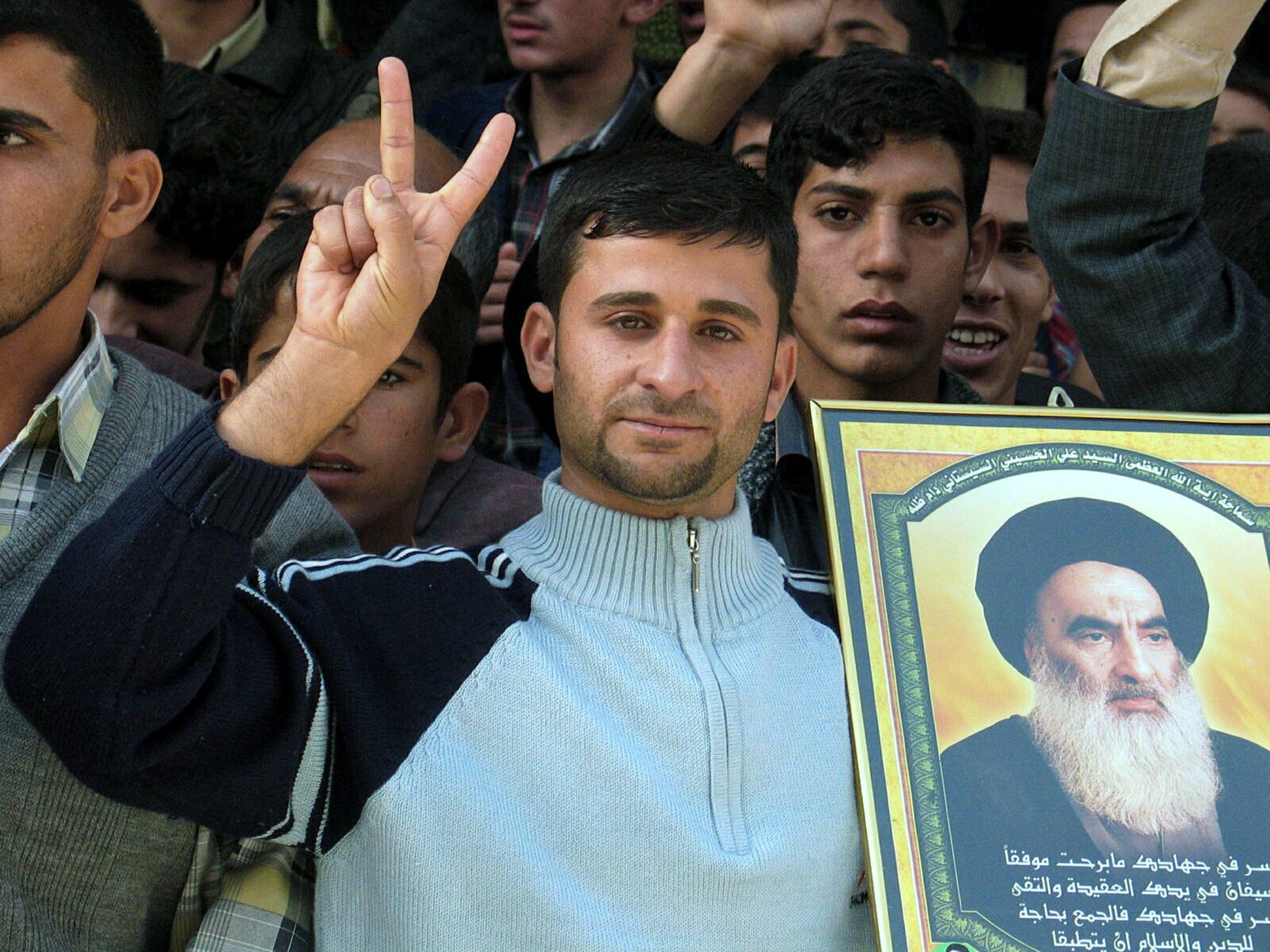 NAJAF, IRAQ - DECEMBER 17:  An Iraqi Shiite man shows getures and holds a picture of Grand Ayotallah Ali al-Sistani as he welcomes Prime Minister Ibrahim al-Jaafari December 17, 2005 in the holy Shiite city of Najaf, Iraq. Al-Jaafari arrived in Najaf on December 17 and visited Ayatollah al-Sistani and the firebrand Shiite cleric Moqtada al-Sadr. (Photo by Saad Serhan /Getty Images)