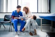 A nurse showing digital tablet to mother and child in a hospital.