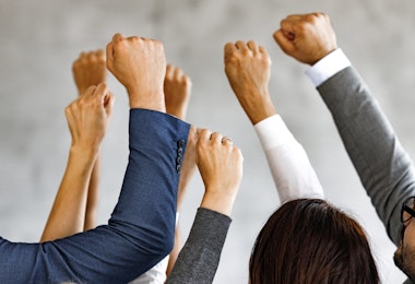 Large group of unrecognizable business people with raised fists.