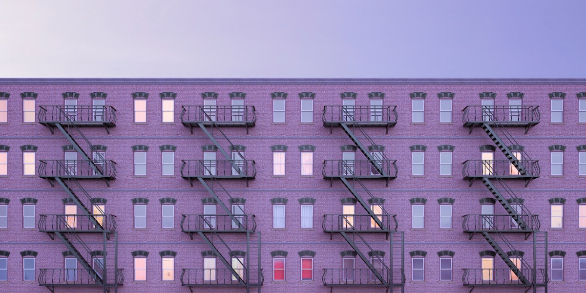 A wide shot view of a multi-family housing structure with fire escapes.