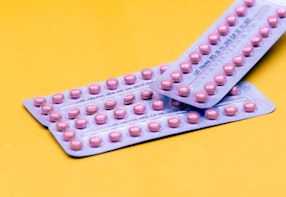 Two blister packs of contraceptive pills on a yellow background.