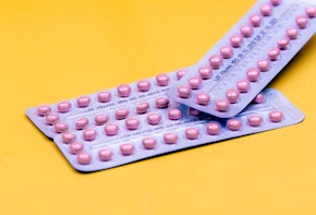 Two blister packs of contraceptive pills on a yellow background.