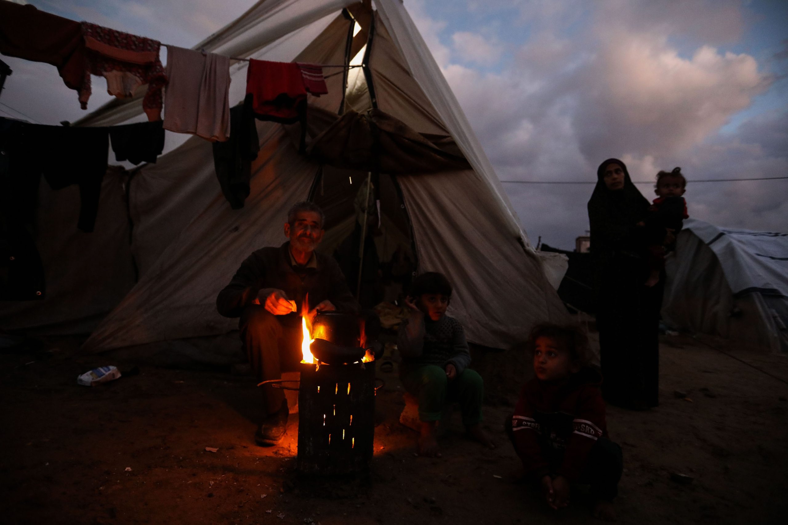 RAFAH, GAZA - JANUARY 23: Displaced Palestinians keep warm by a fire near their tent on January 23, 2024 in Rafah, Gaza. The toll since the Oct. 7 war in Gaza between Israel and Hamas now exceeds 25,000 dead and 62,000 injured, according to the territory's health ministry. Two-thirds of the victims are believed to be women and children. The United Nations estimates for its part that more than 18,000 Palestinian children have lost a parent. With 25 per cent of the population, or more than half a million people, are in a situation of 