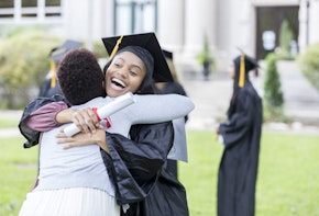 Excited college graduate hugs her mom after the graduation ceremony.