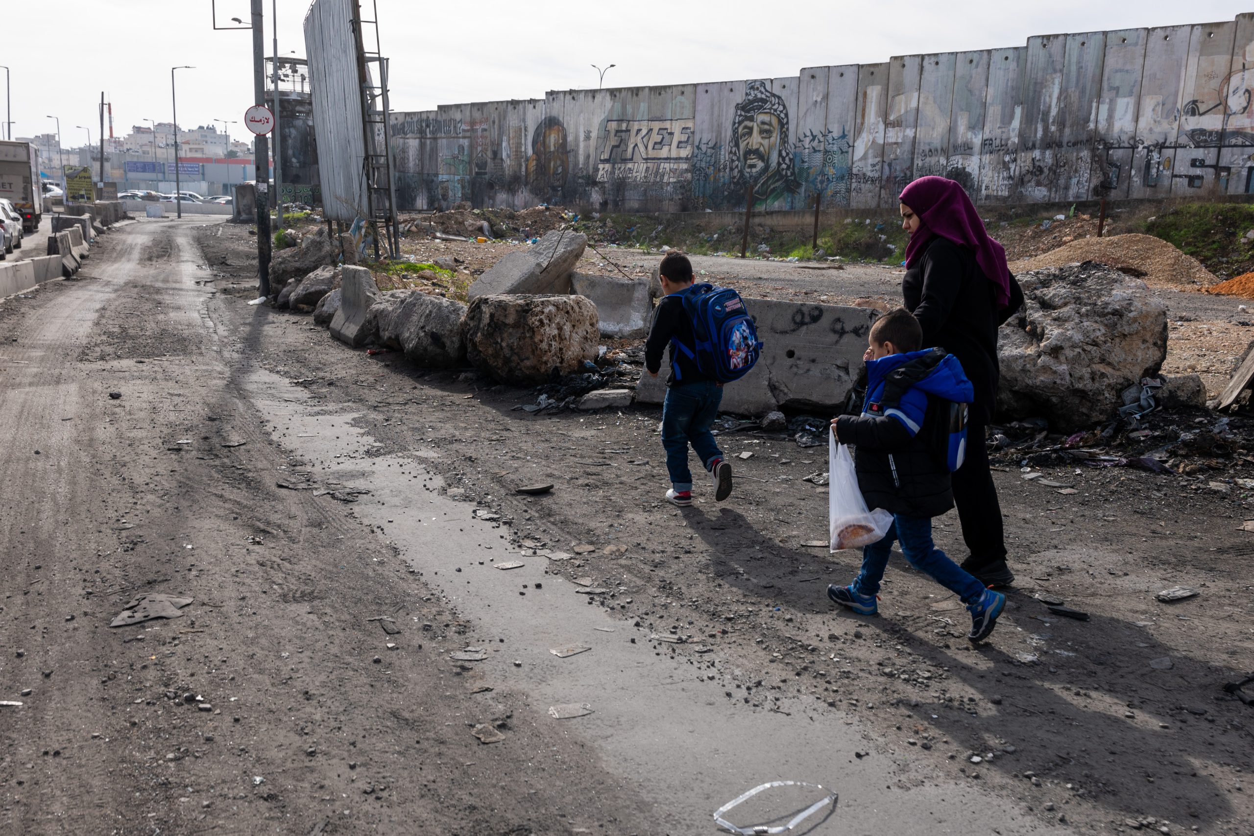 RAMALLAH - DECEMBER 10: A family walks to a checkpoint to  enter Israel at the Qalandia checkpoint outside of the city of Ramallah on December 10, 2023 in Ramallah, Palestine. Israel's war against Hamas that was sparked by the Oct. 7 attacks has also made life more volatile in East Jerusalem and the West Bank. Israeli forces here have stepped up raids on alleged militants, police have clashed with protesters, and there has been a rise in violent attacks on Palestinians by Israeli settlers. Last month, Hamas also claimed responsibility for a deadly shooting in Jerusalem by two brothers from the eastern part of the city. (Photo by Spencer Platt/Getty Images)