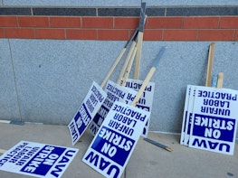 Labor union on strike picketing signs resting on a wall.