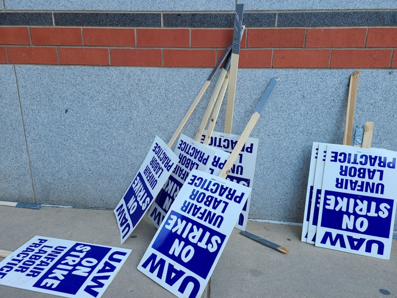 Labor union on strike picketing signs resting on a wall.