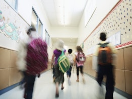 Young students with backpacks walking down hallway of elementary school