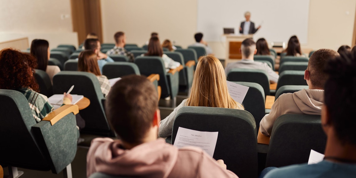 Back view of large group of students paying attention on a class at lecture hall.
