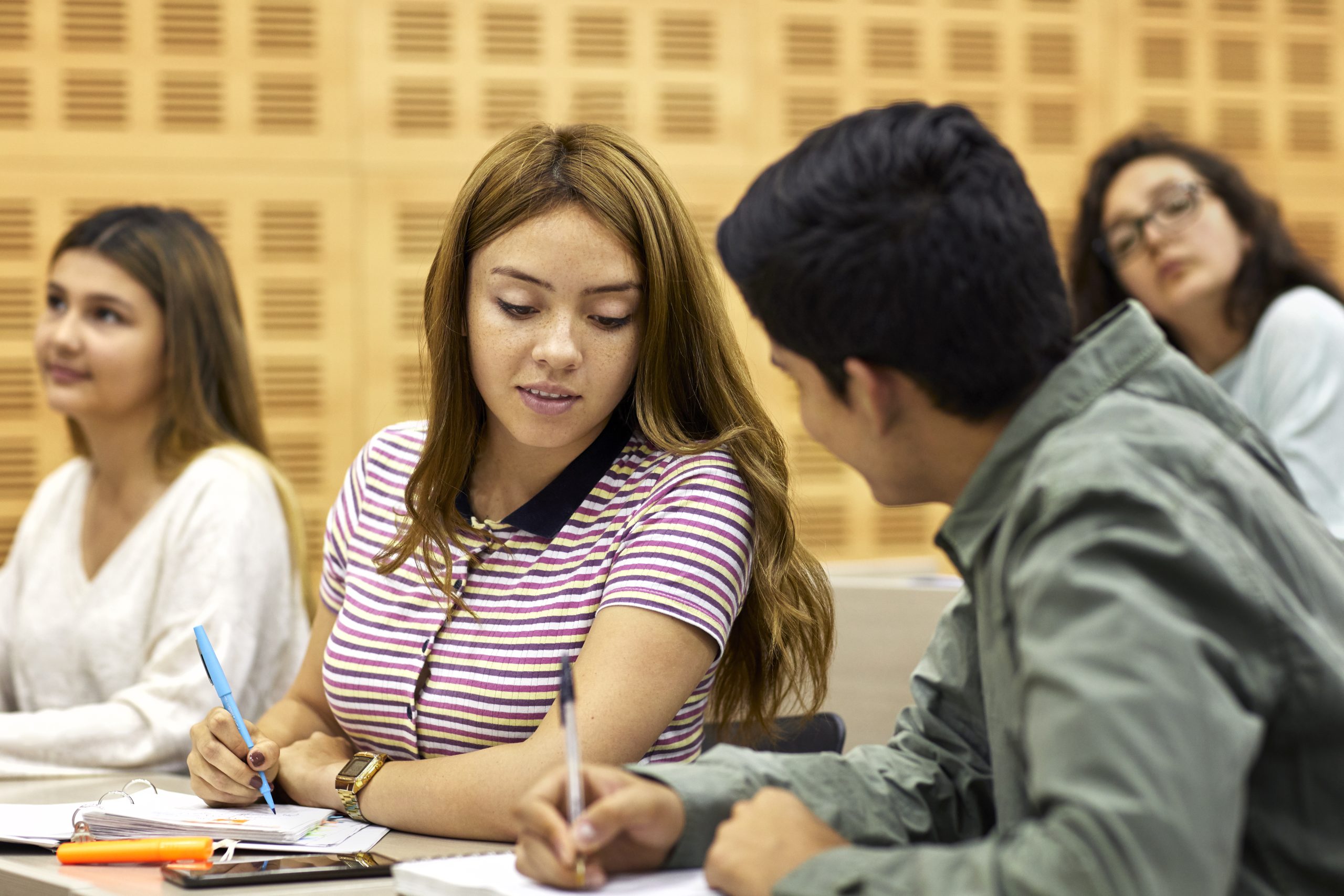 Young male and female students discussing over book. Man and woman are studying together in university. They are wearing casuals.
