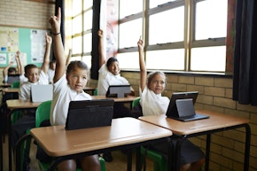 School children in uniforms in class with tablets