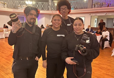 Four members of the Photography Without Borders afterschool program pose with their cameras