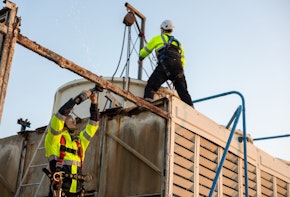 Rooftop Demolition Project: Two Engineers at Work on Dismantling a Cooling Tower. Exploring the Complexities of Industrial Engineering, Safety Protocols, and Team Effort Required for Building Renovation and Maintenance in a Cityscape