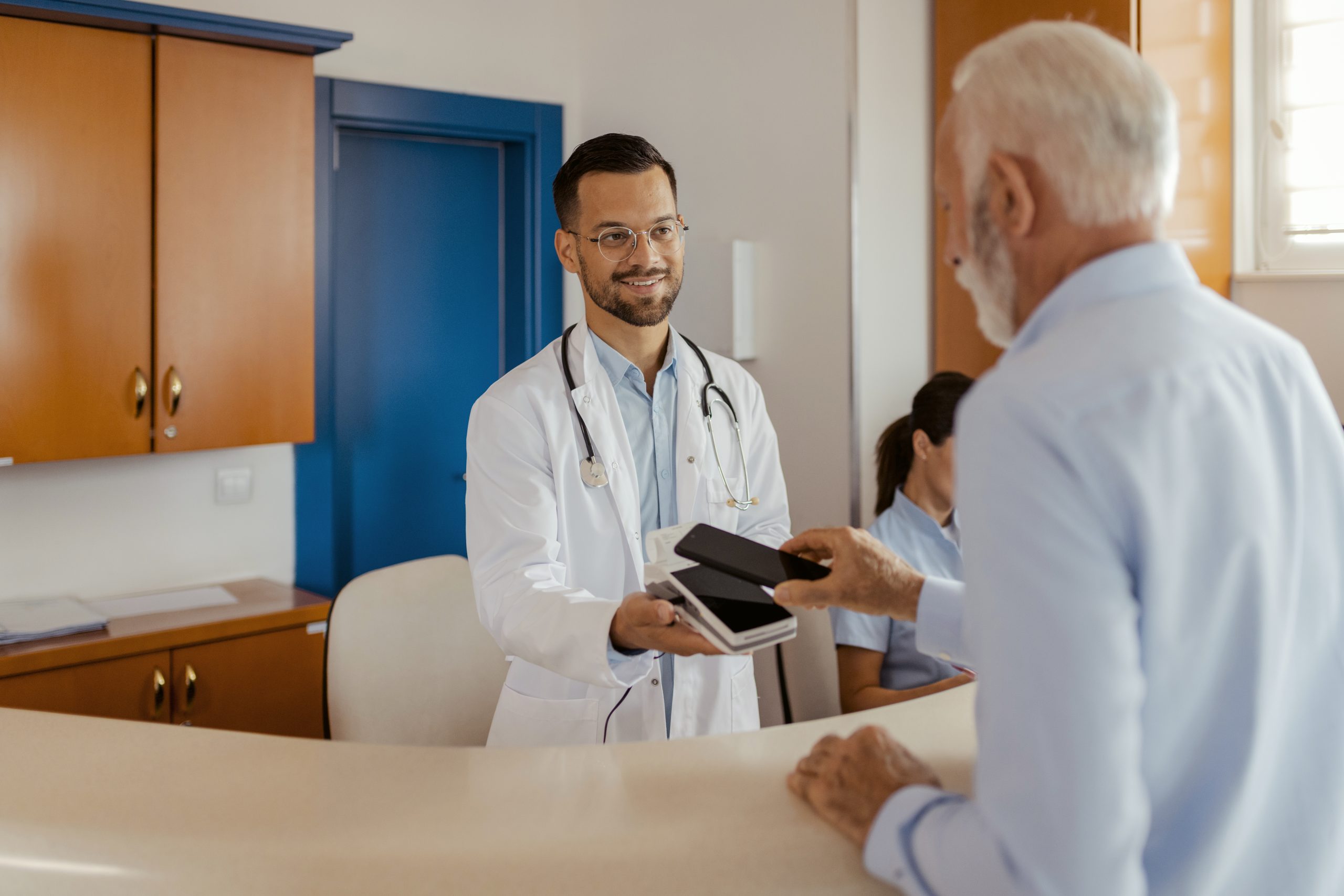 Senior Old Patient Making Electronic Transation and Payment for Checkup at Registration Desk.