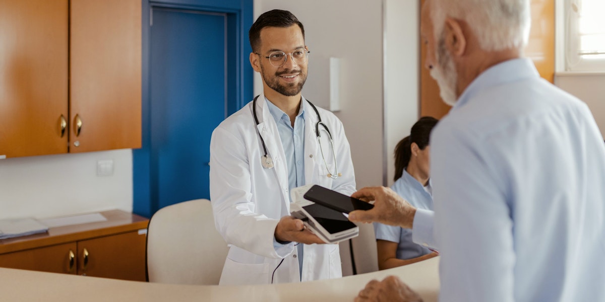 Senior Old Patient Making Electronic Transation and Payment for Checkup at Registration Desk.