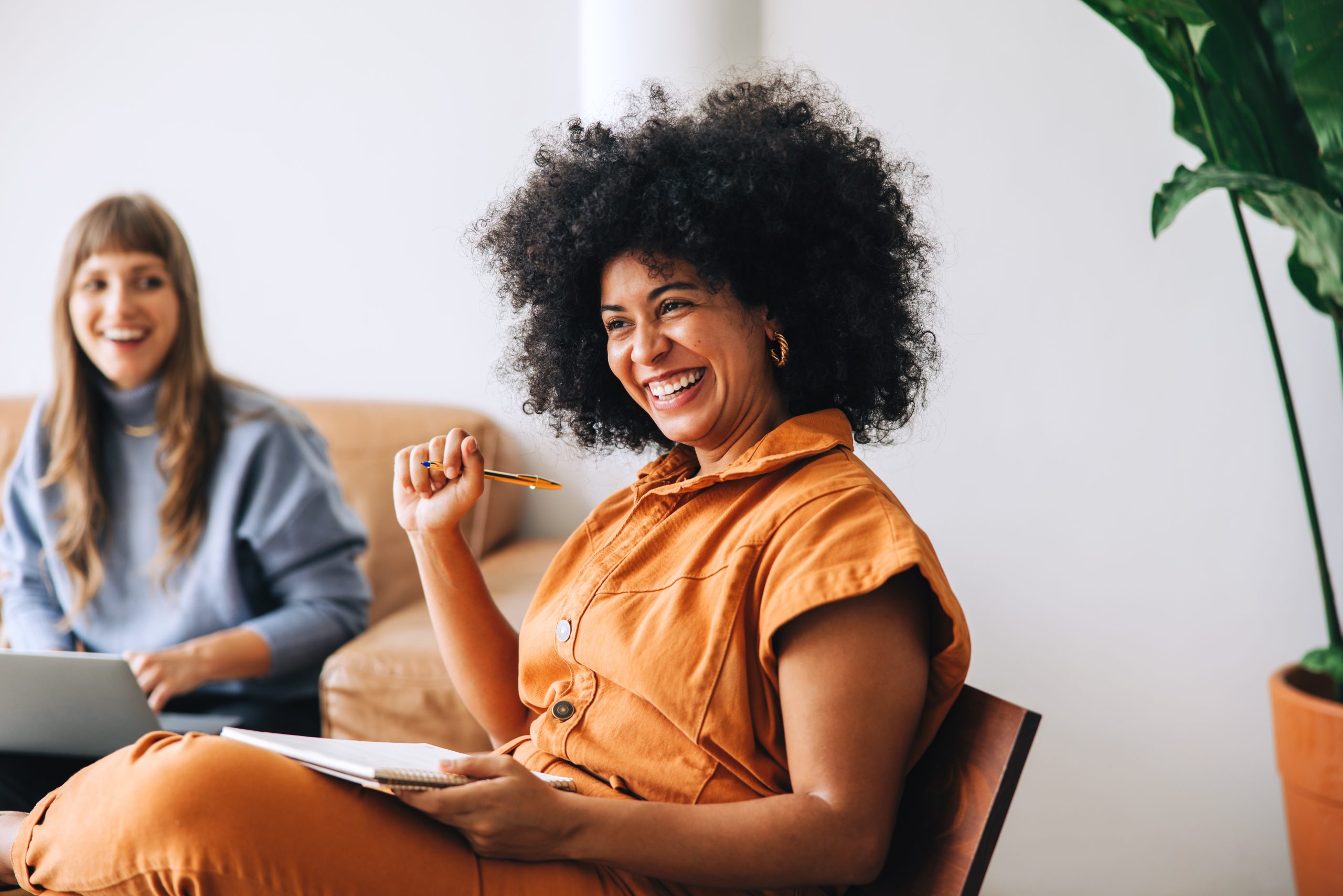 Businesswoman smiling happily while sitting in a meeting with her colleague. Cheerful young businesswomen working together in a modern workplace.