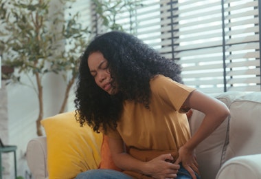 A focused medical professional in a home office environment, scrutinizing a prescription bottle while entering medical data on her laptop. The scene conveys her responsibility in ensuring accuracy in patient medication records, an essential part of healthcare management. The shelf of medical books in the background hints at a commitment to continuous learning and staying updated in the medical field. This footage is relevant for narratives on healthcare diligence, medication management, and the critical role of clinicians in patient safety