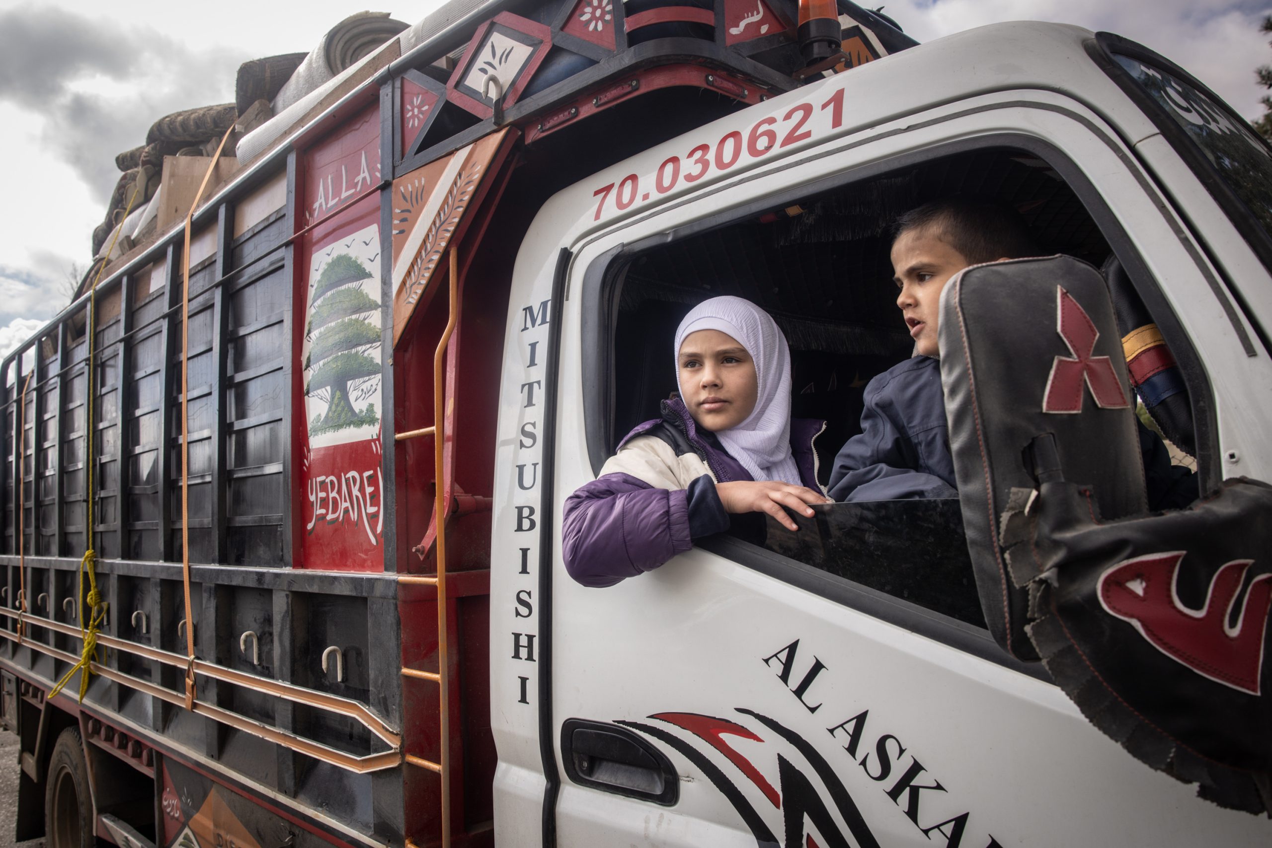 DAMASCUS, SYRIA - DECEMBER 21: 13-year-old Lana who was born in Syria and her brother 6-year-old Muhammad who was born in Lebanon wait in a truck carrying the family's possessions as their father Ahmed Muhammad Al-Nawa prepares papers to cross the border from Lebanon to Syria to return to his family’s home in the village of Harran for the first time in 10-years on December 21, 2024 in Damascus, Syria. 36-year-old Ahmed, was imprisoned and tortured by the regime for a year and half in the Mezzah Military Prison in 2012-2013, after his release, his wife and daughter were displaced from their home in the village of Harran, Eastern Ghouta, Damascus, during the Assad regime’s siege of the region in 2014. They fled to Lebanon where they have been living in a tent in the Hosh Al-Hareem camp for the past 10-years. Ahmed’s mother Umm Marwan stayed behind in Syria due to a heart condition that stopped her from travelling. While living in Lebanon, Ahmed and his wife had four more children that were born in Lebanon and have never meet their grandmother, other relatives or seen the family home. After the fall of the regime Ahmed decided to return home bringing all his possessions from Lebanon and giving his mother the chance to meet her grandchildren face to face for the first time. (Photo by Chris McGrath/Getty Images)