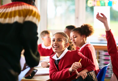 Children sitting at desk as teacher comes to the table, happiness, development, learning