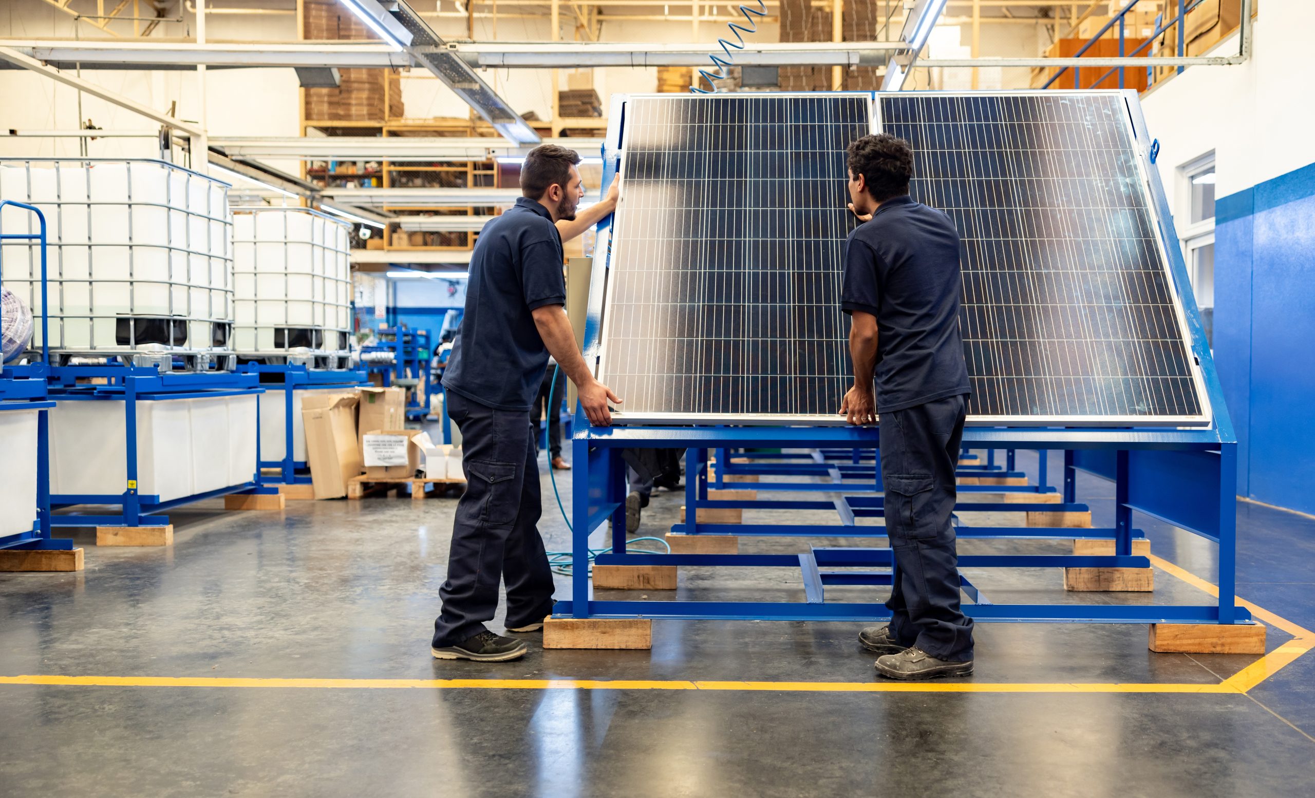 Green technology engineers installing solar panels at a manufacturing factory