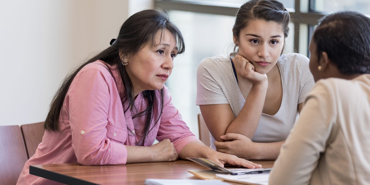 Concerned mother and daughter talking to loan officer at bank.