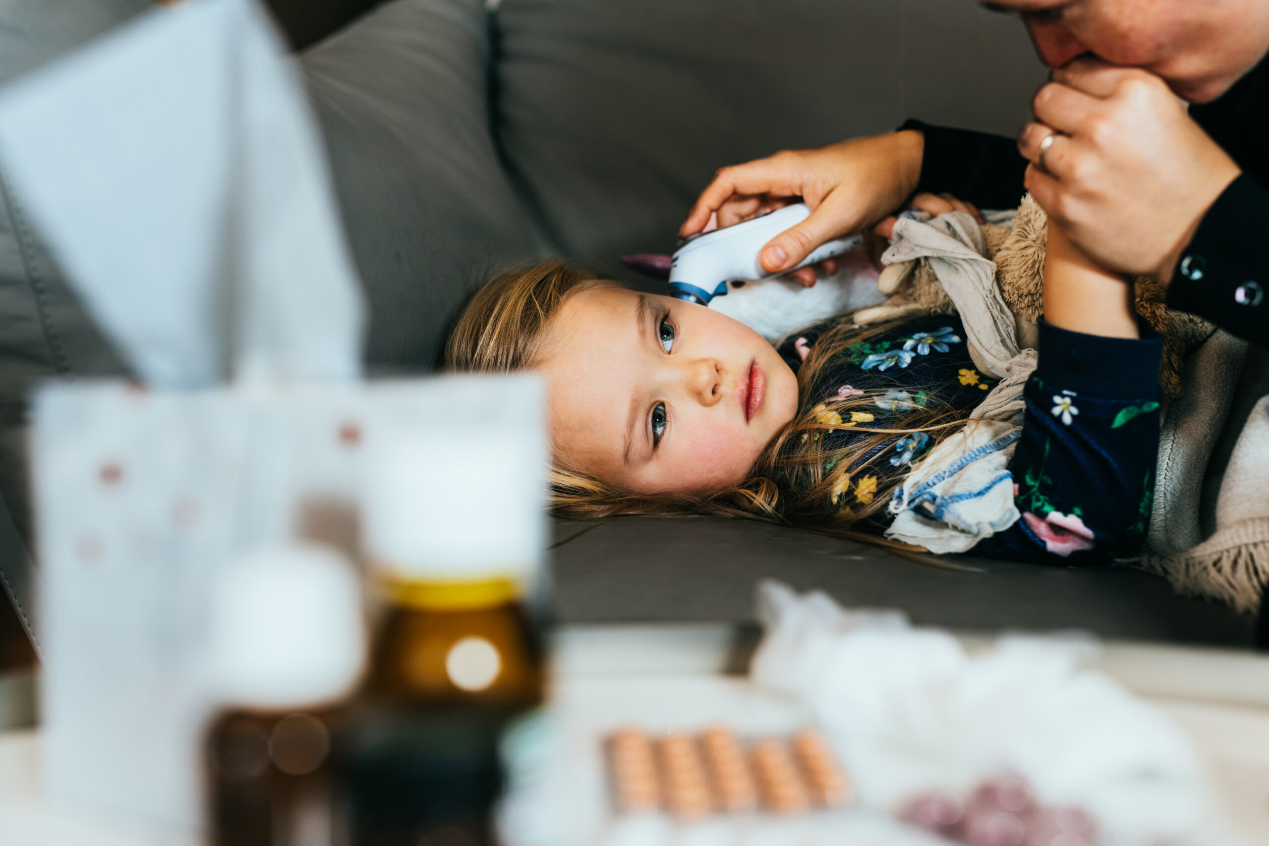Woman using thermometer to check temperature of her child. The girl has a flue and feeling sick.