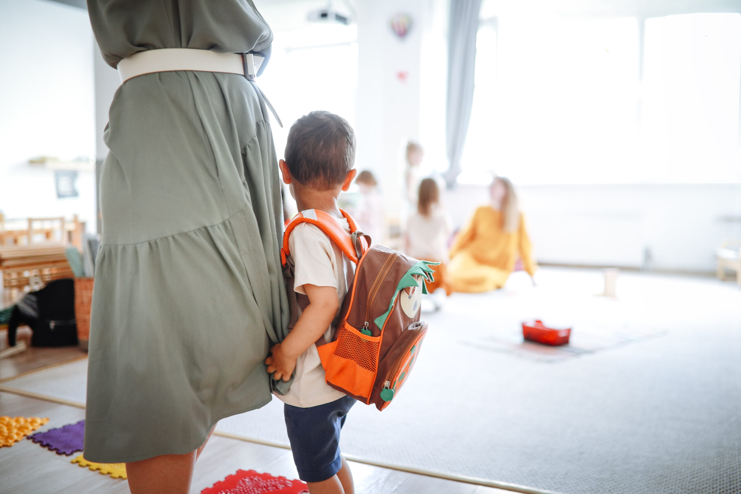 shy child clings to mom at kindergarten, adaptation and adjustment to kindergarten