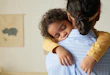 Back view of African American teenage girl holding sleeping little sister in arms while babysitting, copy space