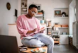 Young woman doing home finances at home in the morning, while having a breakfast