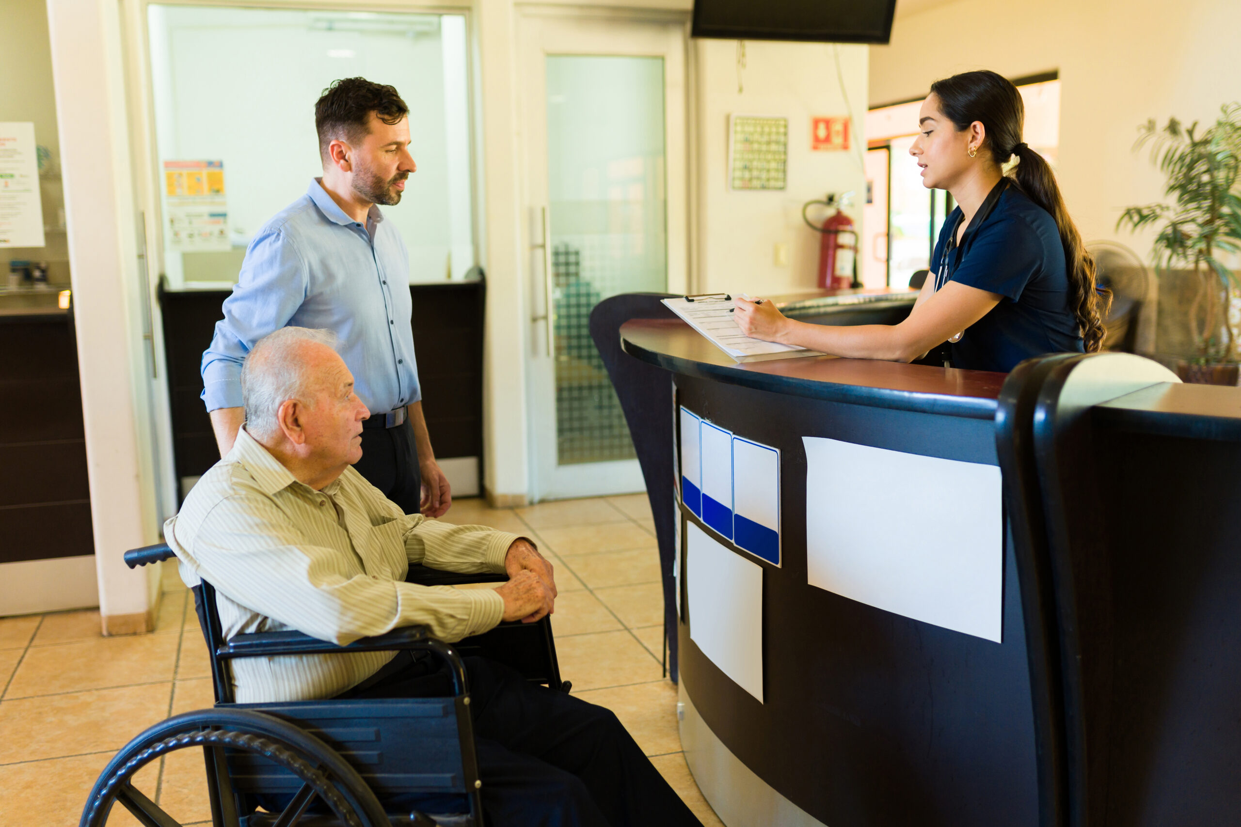 Caucasian young man with an elder mature man in his 80s asking for information at the reception of a retirement home